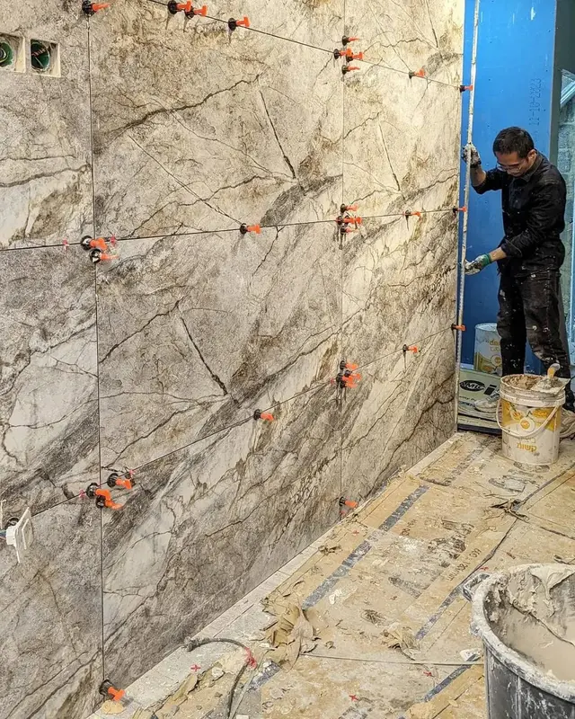 התקנת אריחי שיש על קיר חדר רחצה — עבודה בתהליך